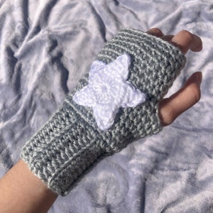 light grey crocheted fingerless gloves with ribbing detail around wrist and white star motif on back of hand