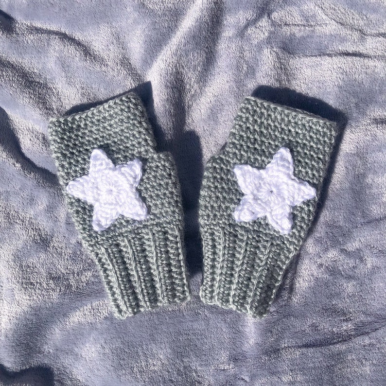 light grey crocheted fingerless gloves with ribbing detail around wrist and white star motif on back of hand