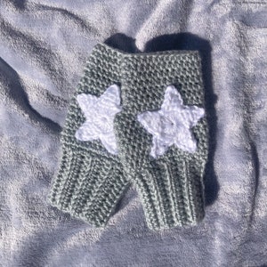 light grey crocheted fingerless gloves with ribbing detail around wrist and white star motif on back of hand