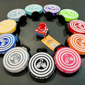 May include: A selection of vibrant car vent clips, each featuring a duck and vehicle motif. The clips are in a range of colours: blue, green, yellow, red, orange, pink, and white. A small red duck figurine and a tag with the text "UP & DUCK" are also visible.