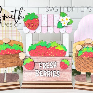 May include: Three wooden gnome figures with strawberry details. The center gnome is a strawberry stand with the text "Fresh Berries". The gnomes are holding baskets of strawberries.