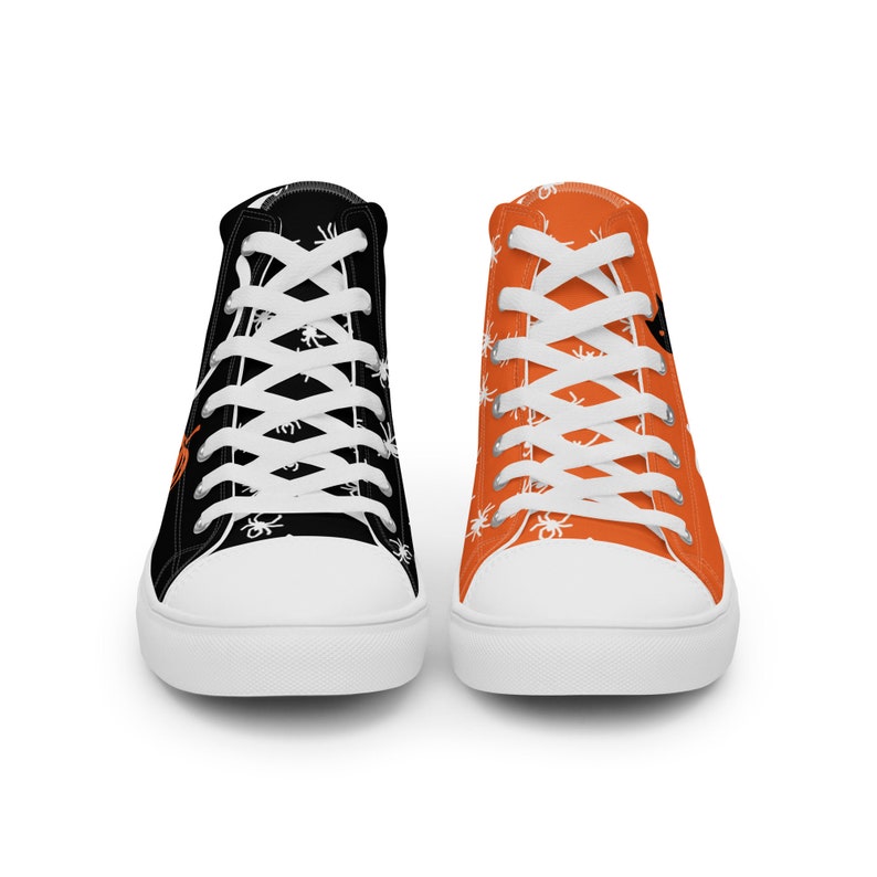 Puede incluir: Par de zapatillas altas de lona. Un zapato es negro con gr&aacute;ficos de ara&ntilde;as blancas y cordones blancos. El otro zapato es naranja con gr&aacute;ficos de ara&ntilde;as blancas y cordones blancos. Las suelas son blancas.