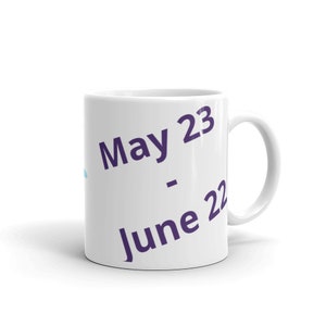 May include: White ceramic mug with the text "May 23 - June 22" printed in purple.