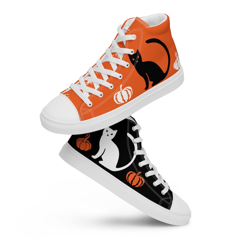 Puede incluir: Dos zapatillas altas de lona. Una es naranja con un gato negro y gr&aacute;ficos de calabaza blanca. La otra es negra con un gato blanco y gr&aacute;ficos de calabaza naranja. Ambas tienen cordones y suelas blancas.