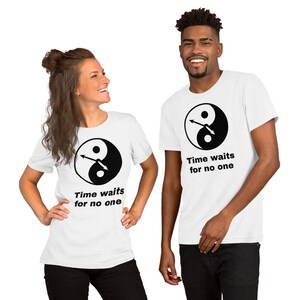 Könnte beinhalten: Zwei weiße T-Shirts mit einem schwarzen Yin-Yang-Symbol und Uhrzeigern. Der Text auf den Shirts lautet "Time waits for no one."