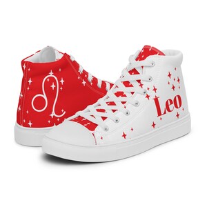 May include: White high-top canvas sneakers with red stars and the Leo zodiac sign. The shoes also have the word "Leo" printed on the side.