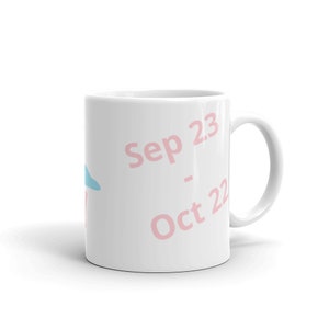 May include: White ceramic mug with a handle. The mug features the text "Sep 23 - Oct 22" in pink, along with a light blue and pink graphic. The mug is designed for hot beverages.