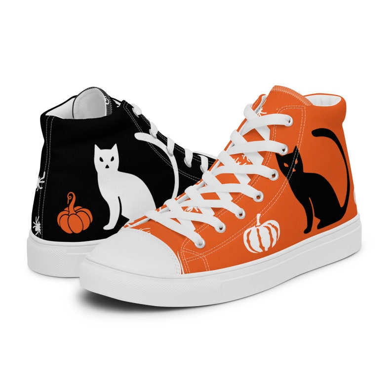 Puede incluir: Zapatillas altas de lona con dise&ntilde;os de Halloween. Una zapatilla es negra con un gato blanco y una calabaza naranja, la otra es naranja con un gato negro y una calabaza blanca. Cordones y suelas blancos.