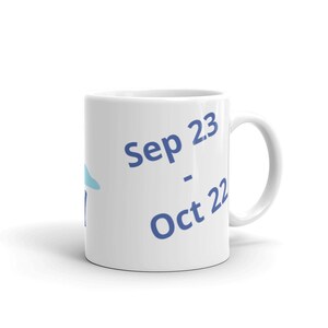 May include: White ceramic mug with blue text that reads "Sep 23 - Oct 22".
