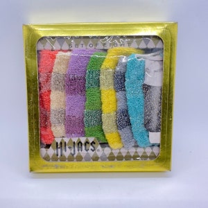 May include: A set of eight colorful washcloths in a gold box. The washcloths are in a rainbow pattern and have a checkered design. The box says "Set of Eight" and "Hi-Jacs".