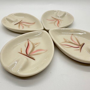 May include: Set of four white ceramic leaf-shaped ashtrays with a pink and brown floral design.
