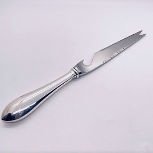 May include: A silver cheese knife with a bottle opener and a serrated edge.