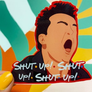 May include: A sticker featuring a cartoon illustration of a man with brown hair and a red shirt, yelling "SHUT UP! SHUT UP! SHUT UP!" The sticker is on a green, yellow, and orange background.