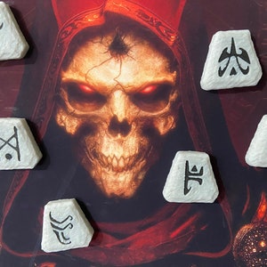 May include: Six white, triangular-shaped stones with black symbols on them. The stones are arranged in a semi-circle around a red and black skull image.