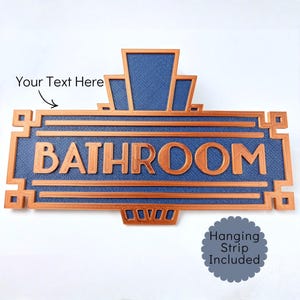 May include: A blue and copper-colored bathroom sign with the word "BATHROOM" in large, raised letters. The sign has an Art Deco design with geometric shapes and a textured background. The sign includes the text "Your Text Here".