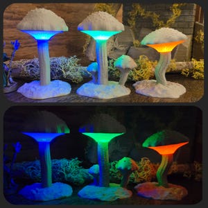 May include: Three white mushroom-shaped lamps with glowing blue, green, and orange lights. The lamps are on a wooden surface and are arranged in a row.