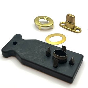 May include: A set of brass snap fasteners with a black plastic tool for installing them. The tool has four different sized punches for different sized fasteners.