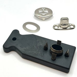 May include: A black plastic tool with four different sized metal tips for setting snaps. The tool is used to attach snaps to fabric. There are also three silver metal snaps, a washer, and a cap.