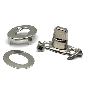 May include: A collection of silver-toned metal hardware components, including a slotted oval plate, a washer, a screw, and a pivoting latch with a screw. The items are arranged on a white background, showcasing their design and construction.