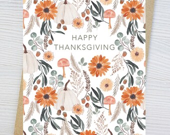 May include: A rectangular greeting card with a white background featuring a watercolor pattern of orange flowers, white pumpkins, mushrooms, acorns, and green foliage. The text HAPPY THANKSGIVING is printed in the center in a simple gray font.