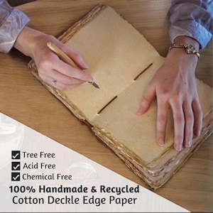 May include: Open handmade journal with deckle edges, being written on with a pen. The paper is a light tan color, and the journal is bound with twine. Text on the image reads: Tree Free, Acid Free, Chemical Free, 100% Handmade & Recycled Cotton Deckle Edge Paper.