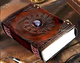 May include: A brown leather journal with a sun and moon design and a blue gemstone in the center. The journal has a Celtic knot border and is closed.