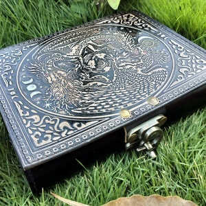 May include: Black leather journal with a silver embossed design of a tree, a bird, and a moon. The journal has a metal clasp.