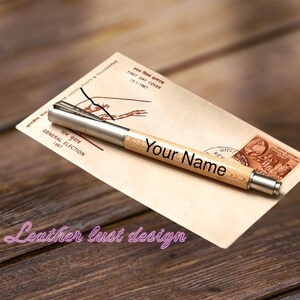May include: A wooden pen with a silver metal tip and a personalized inscription that reads "Your Name". The pen is resting on a vintage envelope with a stamp and text in a foreign language.