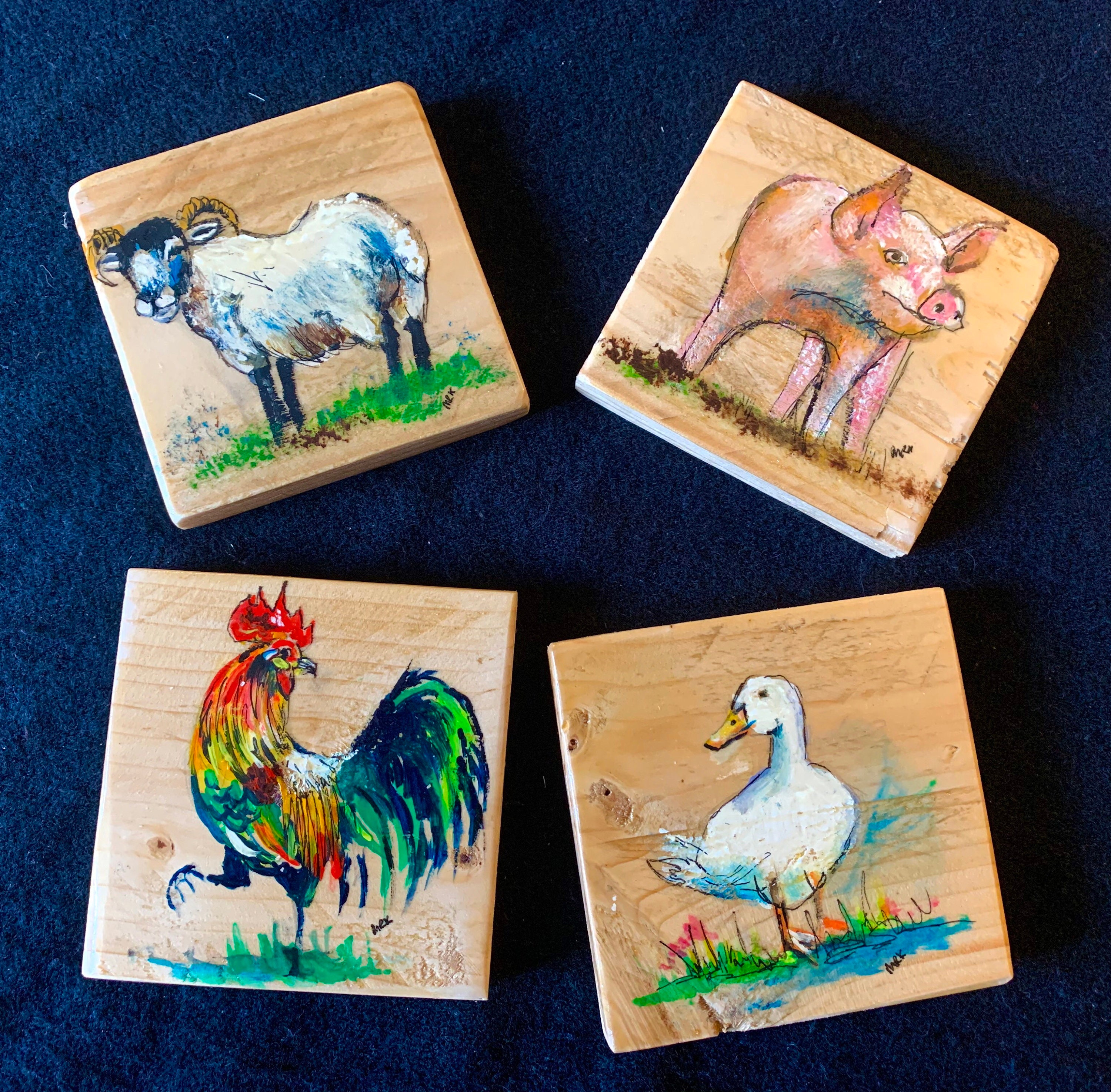 A set of four hand painted coasters on recycled wood depicting Etsy