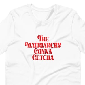 May include: White t-shirt with red text that reads "THE MATRIARCHY GONNA GETCHA"