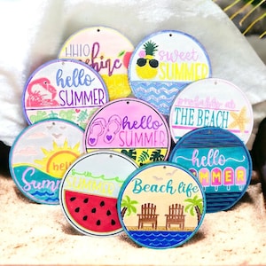 May include: Nine round wooden signs with summer themes. The signs feature various summer-themed designs, including a pineapple, watermelon, beach chairs, flip flops, and a flamingo. The signs are painted in bright colours and have a rustic, handmade look.
