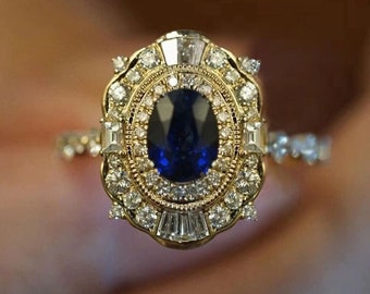 May include: A gold ring with a large oval blue sapphire surrounded by smaller diamonds. The ring has a detailed design with intricate details.