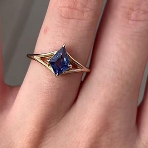 May include: A gold ring with a blue gemstone set in a unique, geometric design.