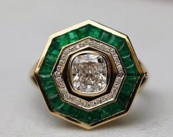 May include: Octagonal engagement ring with a large, cushion-cut diamond center stone. The ring is set in yellow gold and features a double halo of smaller diamonds and emerald green stones.