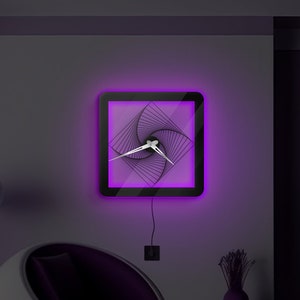 May include: A modern wall clock with a black frame and a geometric design. The clock has a purple LED backlight and silver hands.