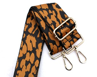 May include: A brown and black leopard print adjustable strap with gold metal hardware, including a buckle and two swivel clips.
