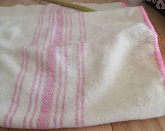 Op de afbeelding: Witte deken met roze strepen. De deken is gemaakt van een zacht, pluche materiaal en heeft een roze rand.