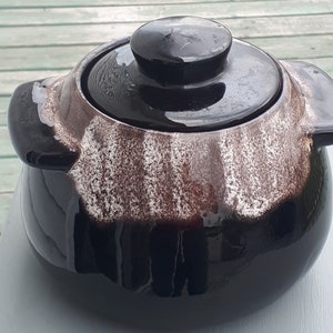 Peut inclure: Un pot en céramique à rayures noires et blanches avec un couvercle. Le pot a une finition brillante et est décoré de rayures brunes et blanches.