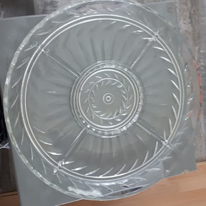 Peut inclure: Un plat de service en verre transparent avec un motif de feuilles décoratif. Le plat a un compartiment central et quatre compartiments plus petits autour du bord.