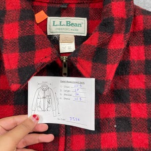 Op de afbeelding: Rood en zwart geruit L.L.Bean jack met ritssluiting. Het label luidt "L.L.Bean FREEPORT, MAINE". Afmetingen: borst 57 cm, lengte 76 cm, schouder 51 cm, mouw 57 cm. De jas heeft een label met afmetingen in inches.
