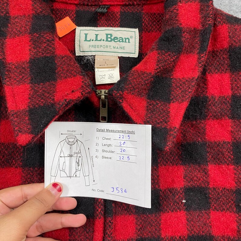 Op de afbeelding: Rood en zwart geruit L.L.Bean jack met ritssluiting. Het label luidt "L.L.Bean FREEPORT, MAINE". Afmetingen: borst 57 cm, lengte 76 cm, schouder 51 cm, mouw 57 cm. De jas heeft een label met afmetingen in inches.