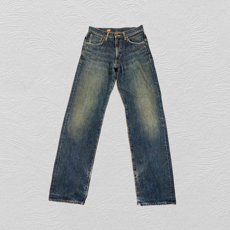 May include: Blue denim jeans with a faded wash. The jeans have a classic five-pocket design, a button and zipper closure, and a straight leg. The denim has a worn appearance, with lighter areas on the thighs and knees.