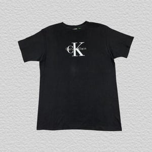 Vintage jaren 90 Calvin Klein T-shirt met groot logo zwart maat M, pasvorm L Gemaakt in de VS | Vintage CK T-shirt met grafische print uit de jaren 90, minimalistische streetwear-mode