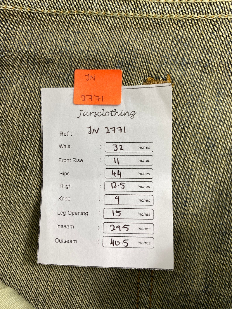 May include: A white tag with black text listing measurements in inches for a pair of jeans. The tag includes the following measurements: Waist: 32 inches, Front Rise: 11 inches, Hips: 44 inches, Thigh: 12.5 inches, Knee: 9 inches, Leg Opening: 15 inches, Inseam: 29.5 inches, Outseam: 40.5 inches.