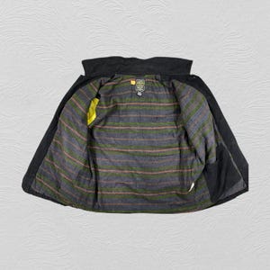 May include: A dark grey jacket with a black collar and interior pockets. The inside lining features a striped pattern in grey, green, and brown. A yellow accent is visible on the inside. The jacket is open, displaying the interior lining.