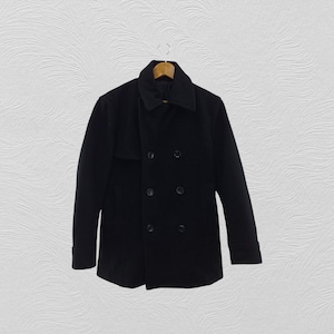 Peut inclure: Un manteau noir à double boutonnage avec un large col et quatre boutons visibles. Le manteau est suspendu à un cintre en bois sur un fond blanc. Le manteau semble être fait d'une matière épaisse et chaude.