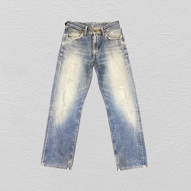 May include: Faded blue denim jeans with a straight leg cut. The jeans have a worn appearance with light distressing and fading throughout. Features include a button closure, belt loops, and classic five-pocket styling. The jeans are a medium wash.