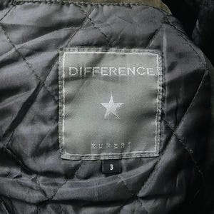 May include: Close-up of a quilted jacket lining. A rectangular label with the word "DIFFERENCE" is stitched on the lining. Below the word is a star and the name "RUPERT". The number "3" is below the name.