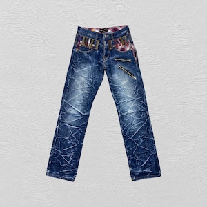 May include: Blue denim jeans with a plaid waistband and zipper details. The jeans have a distressed look.