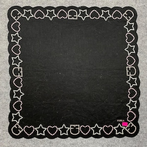 Peut inclure: Foulard carré noir avec bordure festonnée. La bordure est ornée d'étoiles et de cœurs blancs, chacun souligné de petits points blancs. Le foulard porte une étiquette Furla dans le coin inférieur droit.